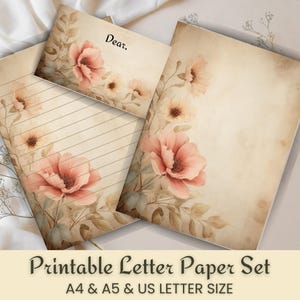 May include: A printable letter paper set featuring a vintage design with floral accents. The set includes lined paper, blank paper, and an envelope, all adorned with watercolor-style pink flowers and foliage. The text "Dear," is visible on the envelope.