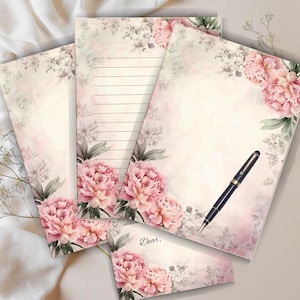 May include: A stationery set with a floral design featuring pink peonies and grey foliage. The set includes lined and blank paper, an envelope, and a pen. The envelope has the word "Dear." printed on it.