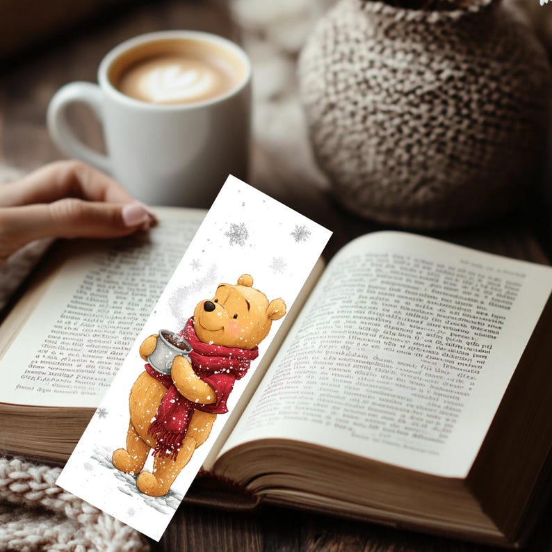 Peut inclure: Un marque-page rectangulaire en papier illustr&eacute; d'un ours jaune portant une &eacute;charpe rouge et tenant une tasse grise. Le dessin pr&eacute;sente des flocons de neige blancs sur fond blanc, repr&eacute;sentant une sc&egrave;ne hivernale avec cet ours.