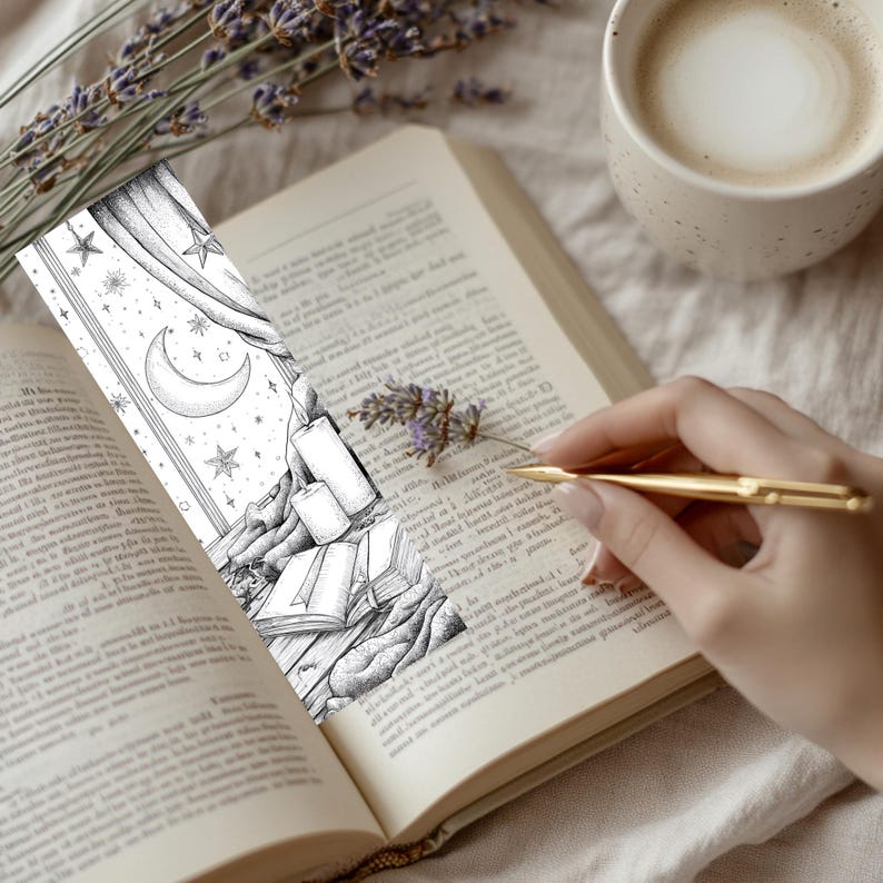 May include: A black and white illustrated bookmark featuring a crescent moon, stars, and candles. The bookmark is placed in an open book with a sprig of lavender and a cup of coffee nearby. A gold pen is held over the book.