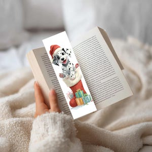 Peut inclure: Un marque-page rectangulaire pr&eacute;sentant une illustration &agrave; l'aquarelle d'un chiot dalmatien portant un bonnet de P&egrave;re No&euml;l rouge, sortant d'une chaussette de No&euml;l rouge. La chaussette est entour&eacute;e de petits cadeaux emball&eacute;s color&eacute;s.