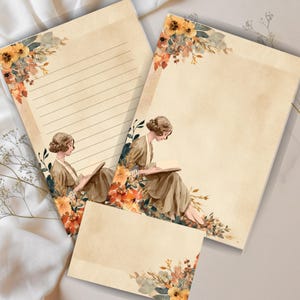 Puede incluir: Juego de papelería con una ilustración vintage de una mujer leyendo, rodeada de arreglos florales en tonos cálidos. El juego incluye papel rayado, papel en blanco y una tarjeta pequeña, todo sobre un fondo crema.