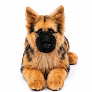 May include: A plush German Shepherd dog toy with realistic tan and black fur, pointed ears, and a black muzzle. The stuffed animal is in a lying position with its front paws extended forward, featuring dark brown eyes and a black plastic nose.