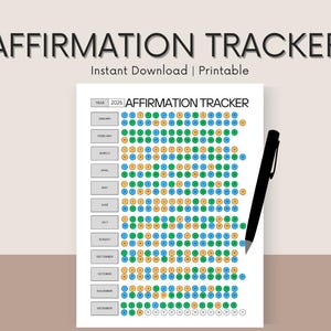 May include: A printable affirmation tracker for the year 2026, featuring a grid of colored circles for each month. The words "AFFIRMATION TRACKER" are at the top. A black pen rests on the right side of the paper.