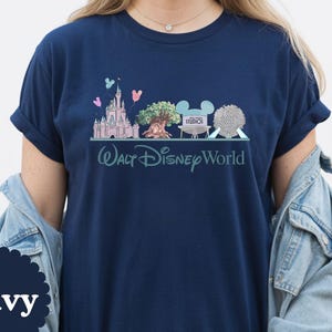 May include: Navy blue t-shirt with a graphic of Walt Disney World landmarks, including Cinderella's Castle, the Tree of Life, and Spaceship Earth. The words "Walt Disney World" are printed below the graphic in a script font.