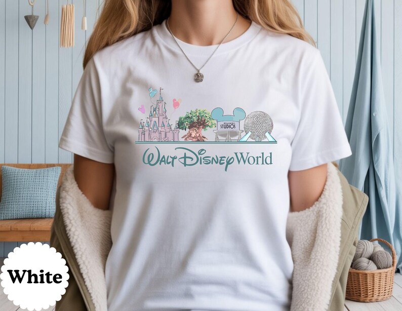 May include: White t-shirt with a colourful illustration of Walt Disney World landmarks, including a castle, tree, and Spaceship Earth. The words "Walt Disney World" are written in a teal script below the images.