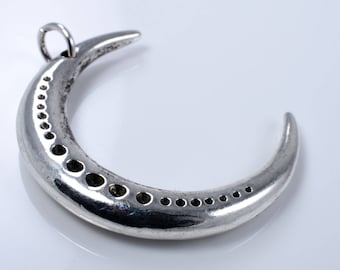 May include: A silver crescent moon pendant with a textured finish and a loop for suspension. The moon features a line of small, evenly spaced holes along its curve. A celestial-themed piece of jewellery.