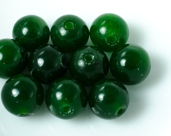 Op de afbeelding: Een groep van tien ronde, groene jade kralen. De kralen zijn glad en gepolijst, met een lichte glans.