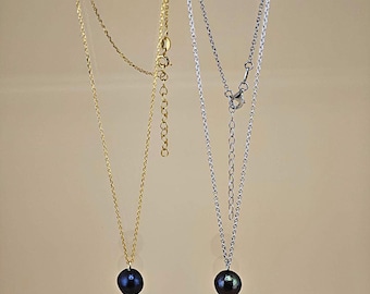 May include: Two delicate necklaces with black pearl pendants. One necklace is gold and the other is silver.