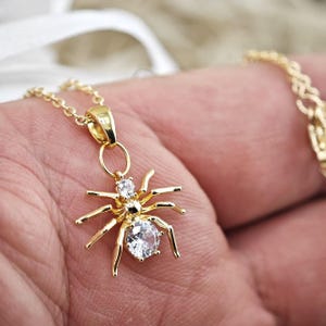Op de afbeelding: Een gouden ketting met een spin-hanger met heldere zirkonia-stenen.
