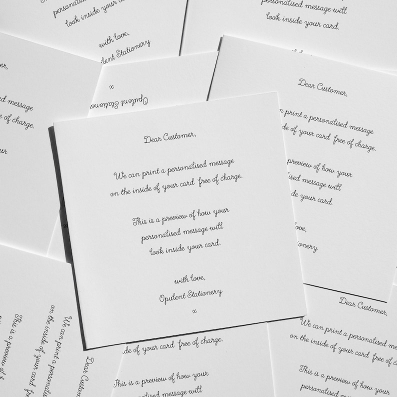 multiple handwritten letters on white cards, with each letter written in a different cursive style. The letters appear to be personalized messages addressed to customers, offering a free card with a personalized message. The cards are spread out, creating a collage-like effect. The text on the cards is written in various fonts and sizes, creating a visually interesting and diverse collection of handwritten messages.