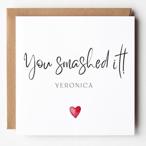 Può includere: Biglietto di auguri bianco con la scritta "You smashed it!" in corsivo nero. Sotto il testo c'è il nome "Veronica" e un piccolo cuore rosso ad acquerello. Il biglietto è in una busta marrone.