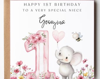 May include: A birthday card with a brown envelope. The card features a pink number one decorated with flowers, an elephant holding a heart-shaped balloon, and a bee. Text reads "Happy 1st Birthday to a very special niece Georgina."