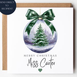 May include: A Christmas card with a watercolour design of a snow globe and a green bow. Inside the globe is a snowy forest and a Christmas tree. The card reads "Merry Christmas Miss Carter" with a green heart.