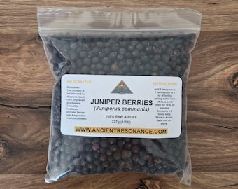 May include: A clear plastic bag filled with dark blue juniper berries. The bag has a white label with text that reads "Juniper Berries (Juniperus communis)" and "100% Raw & Pure 227g (1/2lb)." Instructions are also printed on the label.