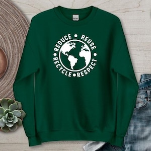 May include: Forest green sweatshirt with a white graphic of the Earth and the words "Reduce, Reuse, Recycle, Respect". The sweatshirt is displayed on a wooden surface with decorative items.