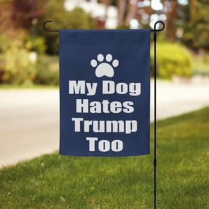May include: A blue garden flag with a white paw print and the text "My Dog Hates Trump Too".