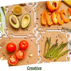 Könnte beinhalten: Vier Holzschneidebretter, jedes mit einer Auswahl an frischen Produkten. Die Bretter zeigen Avocados, Tomaten, Paprika und Spargel. Der Text "INFINITY BOARD KITCHEN" ist auf jedem Brett sichtbar. Das Wort "Creative" steht unten.