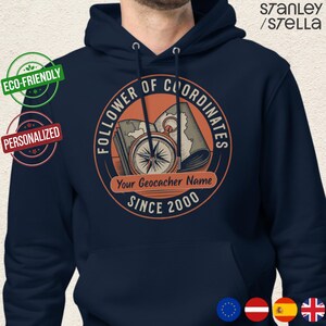 May include: Navy blue hoodie with a circular graphic featuring a compass, map, and the text "FOLLOWER OF COORDINATES." The design includes the text "Your Geocacher Name" and "SINCE 2000." Eco-friendly and personalized labels are also visible.