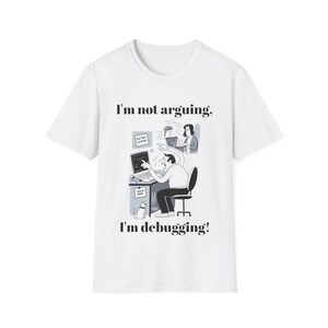 May include: White t-shirt featuring a cartoon of a person debugging code on a laptop. The text says "I'm not arguing, I'm debugging!" A cat is drawn near the desk. The design is in black and white.