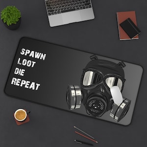May include: Black rectangular mouse pad featuring a gas mask illustration and the text "SPAWN LOOT DIE REPEAT" in white. A white computer mouse is on the pad. The pad is on a dark gray surface.