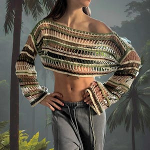 Può includere: Un maglione a maglia all'uncinetto a maniche lunghe e corto, con una vestibilità ampia. Il maglione ha un motivo a righe in tonalità di verde, marrone, bianco e rosa.