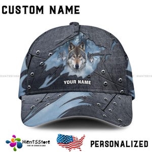 Può includere: Un cappello da baseball grigio e blu con un design in metallo strappato che presenta un lupo e il testo "YOUR NAME".
