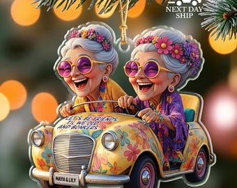 May include: A clear acrylic ornament featuring two smiling elderly women in a yellow car decorated with flowers. The ornament has the text "LET'S BE FRIENDS TIL WE OLD AND BONKERS" and "MAYA & LILY". The ornament is 2D flat.