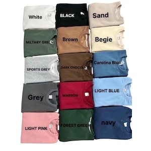 Puede incluir: Una colecci&oacute;n de sudaderas de cuello redondo en varios colores, incluyendo blanco, negro, arena, verde militar, marr&oacute;n, gris deportivo, chocolate oscuro, gris, marr&oacute;n, rosa claro, verde bosque y marino. Cada sudadera tiene una etiqueta con su nombre de color.