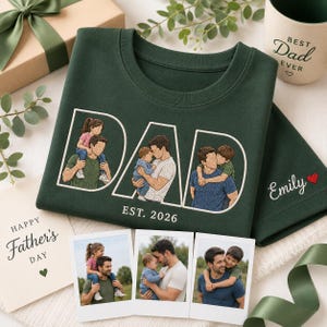 Puede incluir: Camiseta verde oscuro con la palabra "DAD" en blanco, con im&aacute;genes bordadas de un padre con sus hijos. El texto "EST. 2026" est&aacute; debajo de la palabra "DAD". Se ve una taza con "Best Dad Ever".
