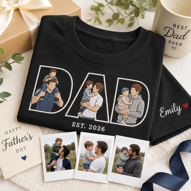 Puede incluir: Camiseta negra con dise&ntilde;o bordado "DAD" con retratos familiares y "EST. 2026". Tambi&eacute;n hay una taza con el texto "Best Dad Ever" y una tarjeta del D&iacute;a del Padre. Incluye tres impresiones fotogr&aacute;ficas y una caja de regalo.