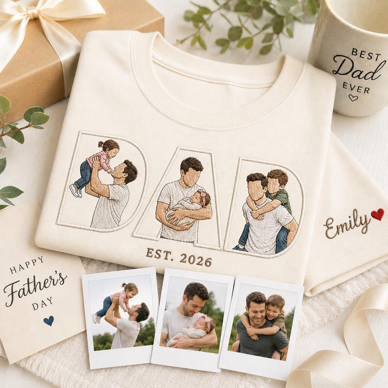 Puede incluir: Sudadera color crema con la palabra "DAD" bordada con ilustraciones de un padre con sus hijos. El texto "EST. 2026" est&aacute; debajo de la palabra "DAD". Una taza con el texto "BEST Dad EVER", una tarjeta que dice "Happy Father's Day" y fotos tambi&eacute;n est&aacute;n en la imagen.