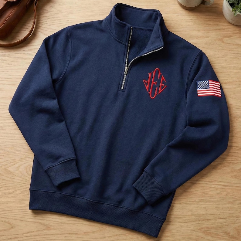 May include: Navy blue quarter-zip sweatshirt with a red embroidered monogram and an American flag patch on the sleeve. The sweatshirt has a ribbed collar and cuffs. The zipper is silver.