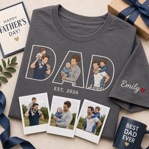 Puede incluir: Una camiseta gris con la palabra "DAD" en blanco, con ilustraciones de un padre con sus hijos. La camiseta incluye "EST. 2026" y el nombre "Emily" con un coraz&oacute;n. Tambi&eacute;n se muestran fotos y una taza que dice "BEST DAD EVER".