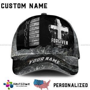 Puede incluir: Una gorra de béisbol negra y gris con el nombre "MICHAEL" en el lateral. La gorra presenta una cruz blanca y la palabra "FORGIVEN" con un versículo bíblico. El texto "CUSTOM NAME" está en la parte superior y "YOUR NAME" en la visera.