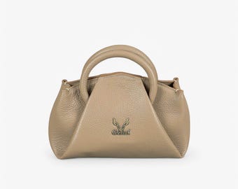 May include: A small, light brown leather handbag with a top handle and a gold logo that says "Genui".