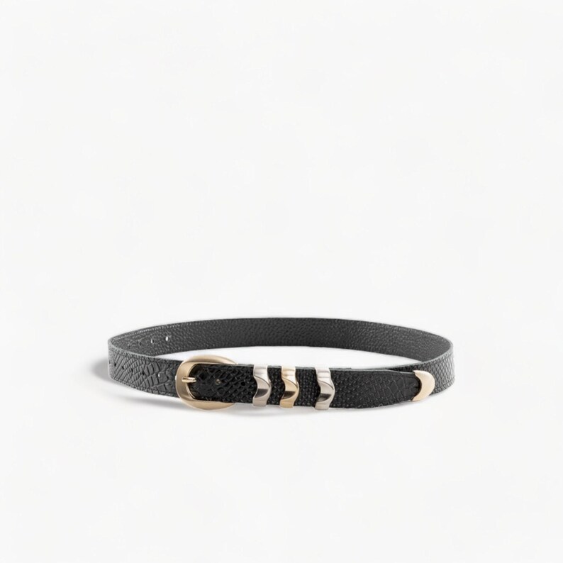 May include: A black leather belt with a gold buckle and silver accents. The belt has a textured finish and is approximately 1 inch wide.