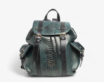 May include: A green leather backpack with black straps and buckles. The backpack has a snakeskin pattern and a gold logo.