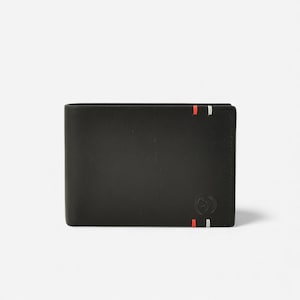 Puede incluir: Cartera de cuero negro con rayas rojas y blancas. La cartera tiene un pequeño emblema en la esquina inferior derecha. La cartera es rectangular y tiene un diseño plegable.