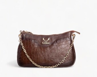 May include: A brown leather handbag with a gold chain strap and a gold logo that says "Genui".