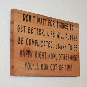 Może przedstawiać: Prostokątna drewniana tablica z napisem "DON'T WAIT FOR THINGS TO GET BETTER. LIFE WILL ALWAYS BE COMPLICATED. LEARN TO BE HAPPY RIGHT NOW, OTHERWISE YOU'LL RUN OUT OF TIME." Tekst jest czarny.