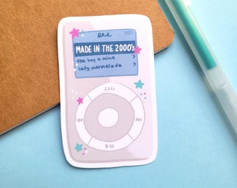 May include: A sticker featuring a retro-style digital music player design. The screen displays the text "MADE IN THE 2000's" and song titles. Pink stars and teal accents decorate the sticker, which is set against a brown and blue background.