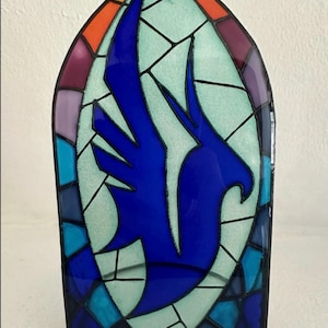 Puede incluir: Un panel de vidrieras en forma de arco, con un diseño de pájaro azul. El panel está enmarcado con una variedad de colores, incluyendo azul, verde, naranja, morado y rojo. El número "3" es visible en la esquina inferior derecha.