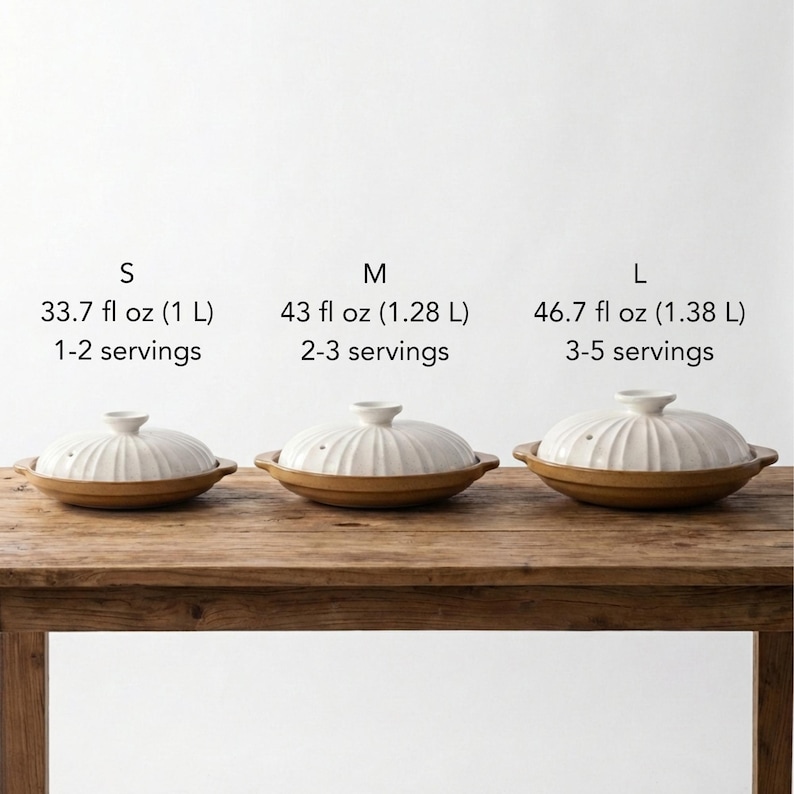 Op de afbeelding: Drie keramische kookpotten met deksels, in verschillende maten, worden getoond op een houten tafel. De potten zijn wit met geribbelde deksels en bruine bodems. Tekst boven de potten geeft maten aan: S (1 L), M (1,28 L) en L (1,38 L), met portie suggesties.