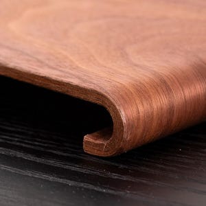 Peut inclure: Gros plan sur une surface en bois incurv&eacute;e, de couleur brun fonc&eacute;. Le veinage du bois est visible, et le bord est arrondi. La surface semble faire partie d'un objet en bois plus grand.