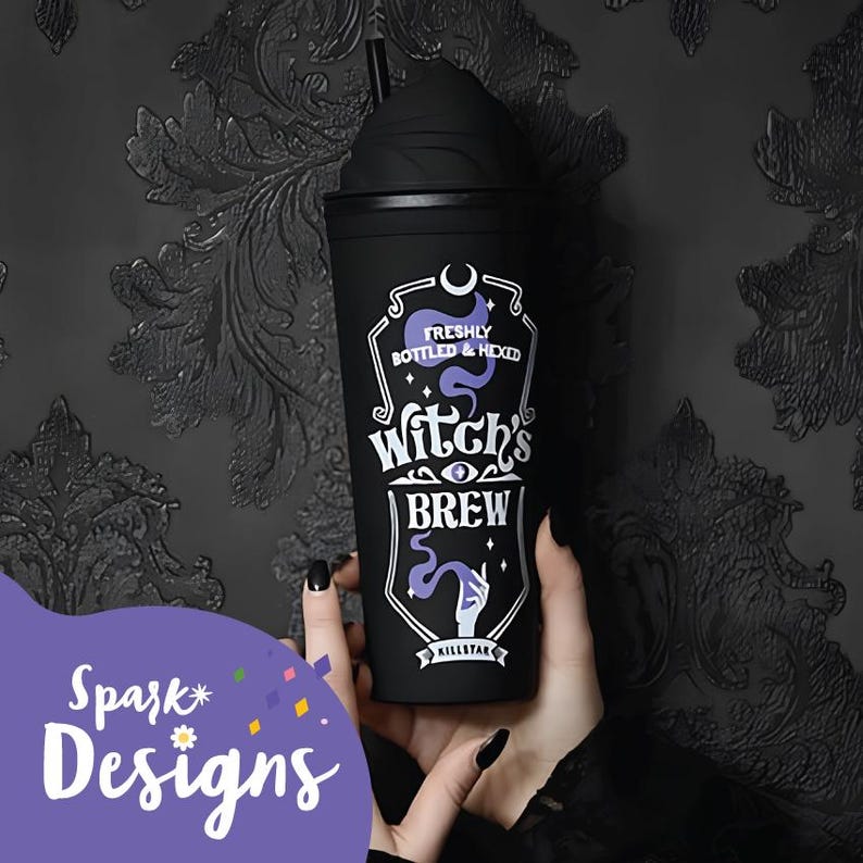 Puede incluir: Vaso reutilizable negro con un gr&aacute;fico morado y blanco que dice "Freshly Bottled & Hexed Witch's Brew" con un ojo morado y una mano sosteniendo una varita. El vaso tiene una tapa negra con una pajita negra.