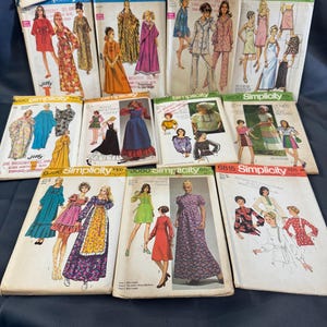 May include: A collection of vintage Simplicity sewing pattern envelopes. The patterns feature illustrations of dresses, jumpsuits, and other garments. The envelopes are in various colors and designs, showcasing fashion trends from the past.
