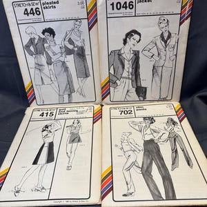 May include: Four vintage sewing pattern packets from Stretch & Sew. The packets feature illustrations of women's clothing, including pleated skirts, tailored jackets, golf and tennis skirts, and slim pants. Each packet has a unique design and number, with text indicating the garment type.