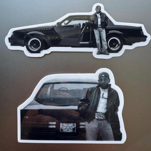 May include: Two black and white stickers. One shows a black car with a person standing next to it. The other sticker shows the back of a black car with a person standing in front of it.