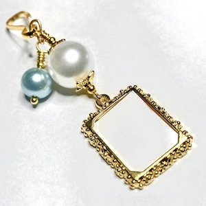 May include: Gold charm with a white pearl, a light blue pearl, and a gold frame with a blank space inside.
